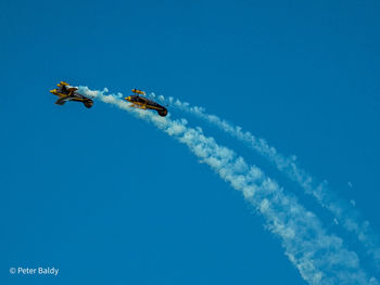 Low angle view of airplane flying against clear blue sky