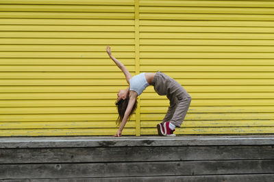 Full length of woman standing on wooden wall