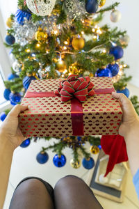 Cropped hand of woman holding christmas decorations on table