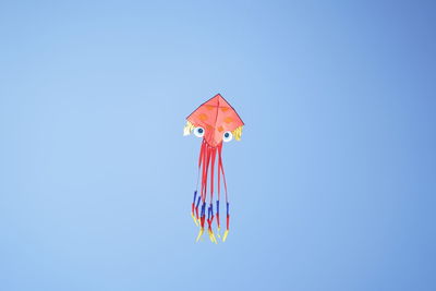 Low angle view of kites flying against clear blue sky