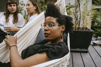 Portrait of woman with friends sitting on hammock in yard during garden party