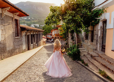 Rear view of woman walking amidst buildings