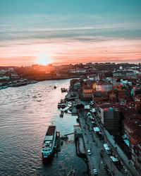 High angle view of cityscape by sea against sky during sunset