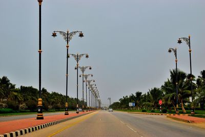 Street lights by road against sky in city