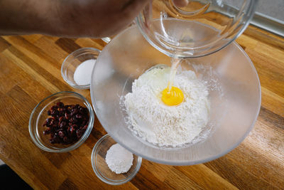 High angle view of person making a cake with egg yolk and flour in mixing bowl on table