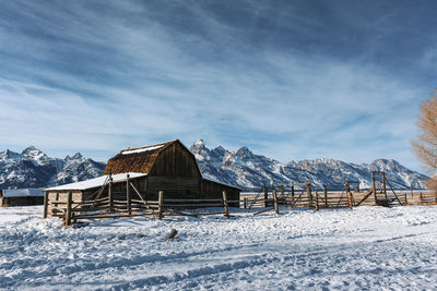 House on snow covered field against sky