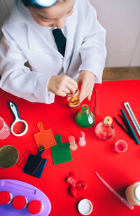 High angle view of boy wearing lab coat while mixing chemicals in classroom