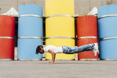 Young man practicing handstand in front of concrete pipes