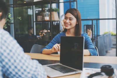 Young woman using phone while sitting on table