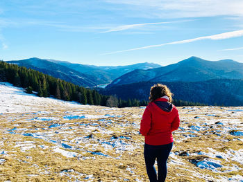 Rear view of woman looking at mountains against sky