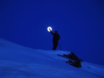 Silhouette man showing peace sign against full moon at night