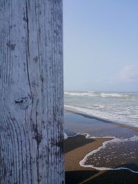 Close-up of wooden posts on beach against sky