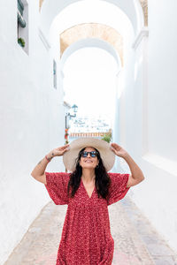 Woman wearing hat standing against wall