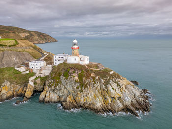 Lighthouse by sea against sky