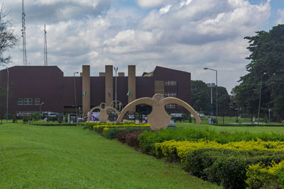 Park by buildings in city against sky