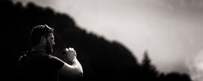 Man photographing mountain against sky