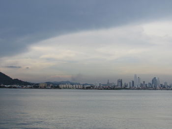 Sea and buildings in city against sky