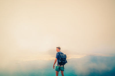 Portrait of young man standing against sky