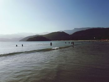 People on beach against clear sky