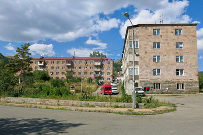 Road by buildings against sky in city