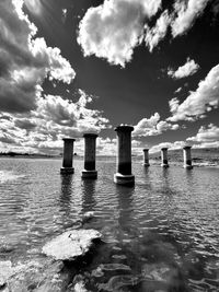 Wooden posts in sea against sky