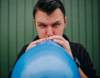 Portrait of young man holding blue eyes