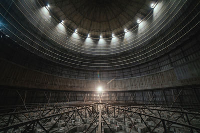 Interior of round dark room with dome and dim lamp inside derelict industrial facility