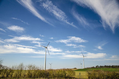 Wind turbines on field against sky