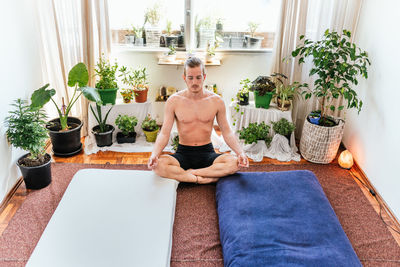 Young man sitting on potted plant