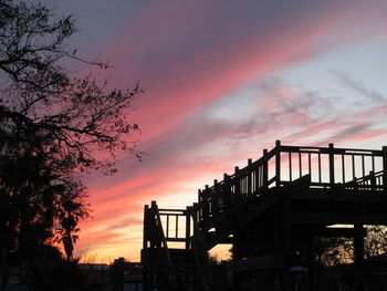 Silhouette built structure against orange sky