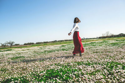 Woman standing on field against clear sky