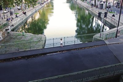 High angle view of woman on footbridge over river in city