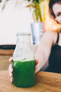 Woman holding drink bottle on table