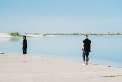 Rear view of man standing on beach against sky