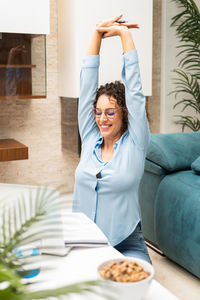 Portrait of young woman using mobile phone while sitting at home