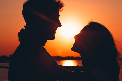 Silhouette couple against orange sky during sunset