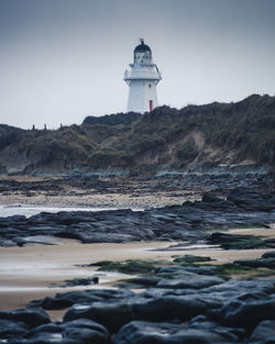 Lighthouse by sea against sky