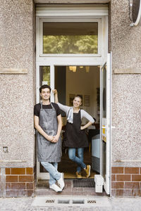 Male and female owners standing together near cafe doorway