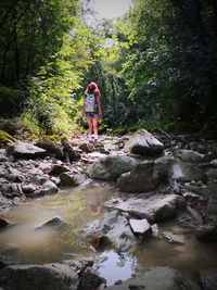 Women standing on rock by stream in forest