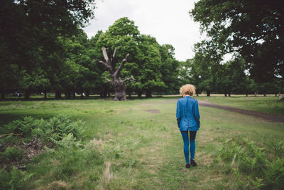 Rear view of girl walking on grassy field