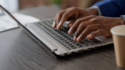 Midsection of man using laptop on table