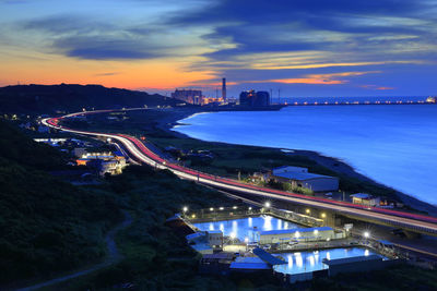 High angle view of illuminated bridge over river against sky at sunset