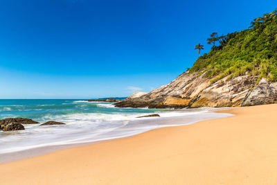 Scenic view of beach against blue sky