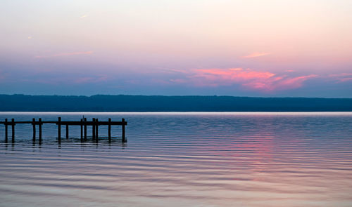 Pier on lake against sky during sunset