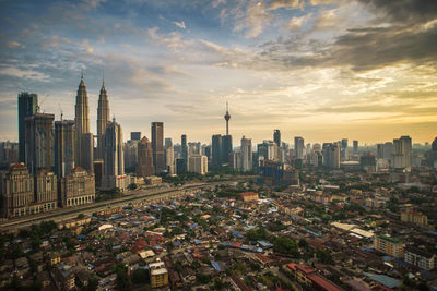 Aerial view of buildings in city against cloudy sky