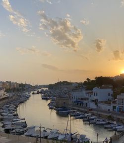 Sailboats moored in harbor against sky during sunset