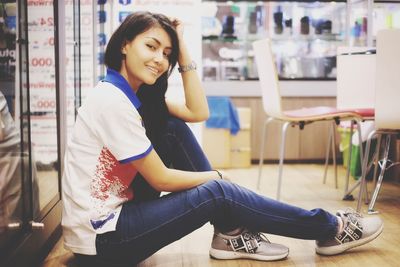 Portrait of smiling young woman sitting on floor