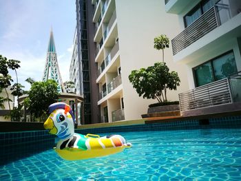 Full length of boy toy in swimming pool against buildings