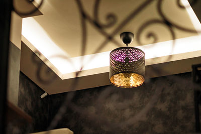 Low angle view of illuminated pendant light hanging on ceiling