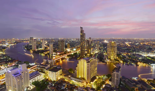 Aerial view of illuminated cityscape against sky at sunset